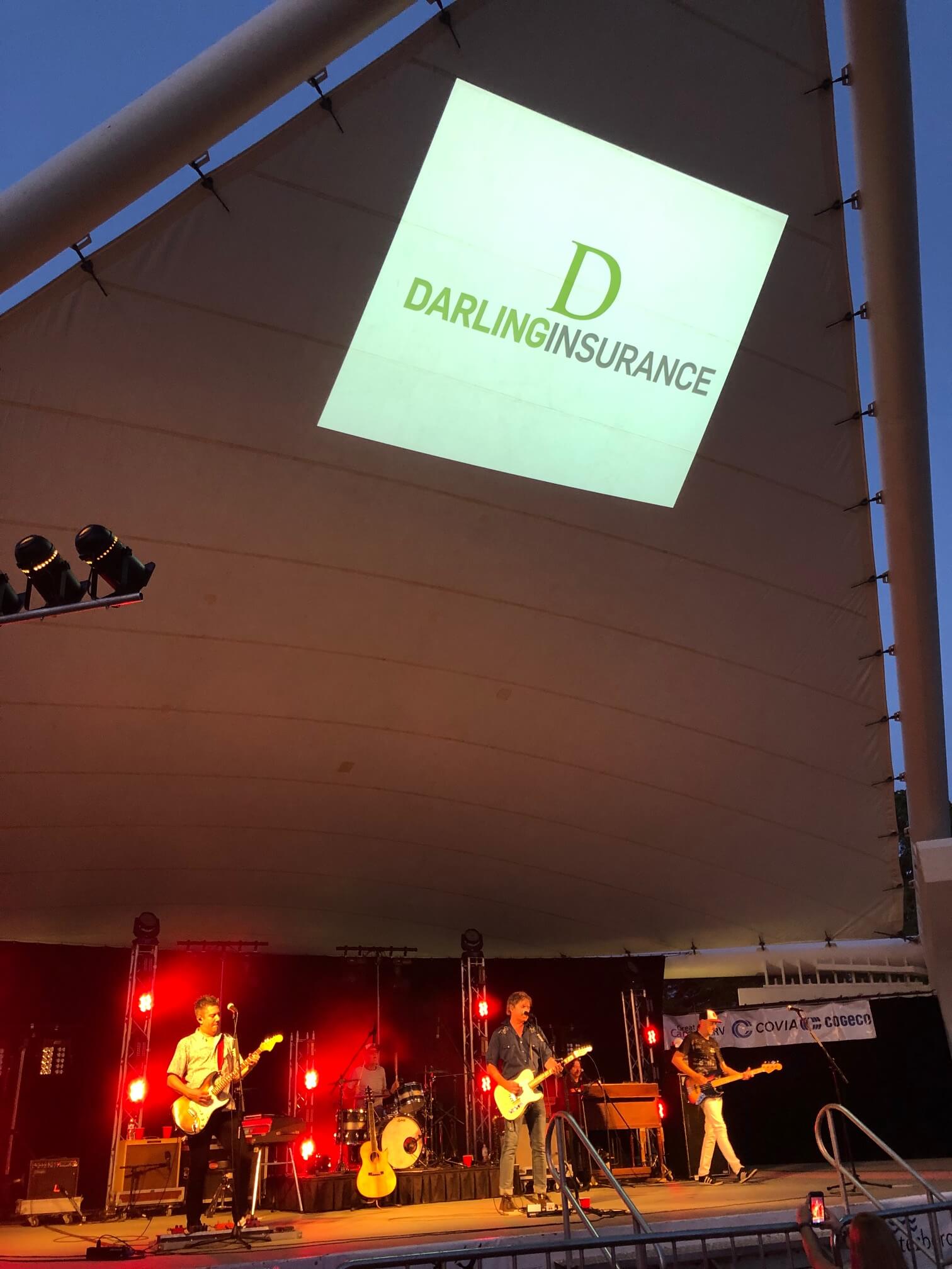 Photo of the musicfest stage with Darling Insurance's logo projected on the roof